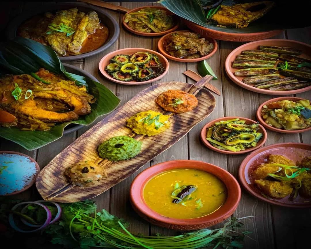 A table of colourful Bangladeshi dishes served in earthen bowls